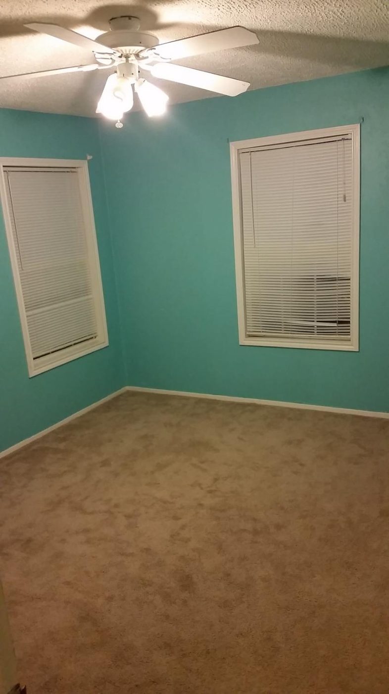 Bedroom painted teal with white trim and ceiling fan